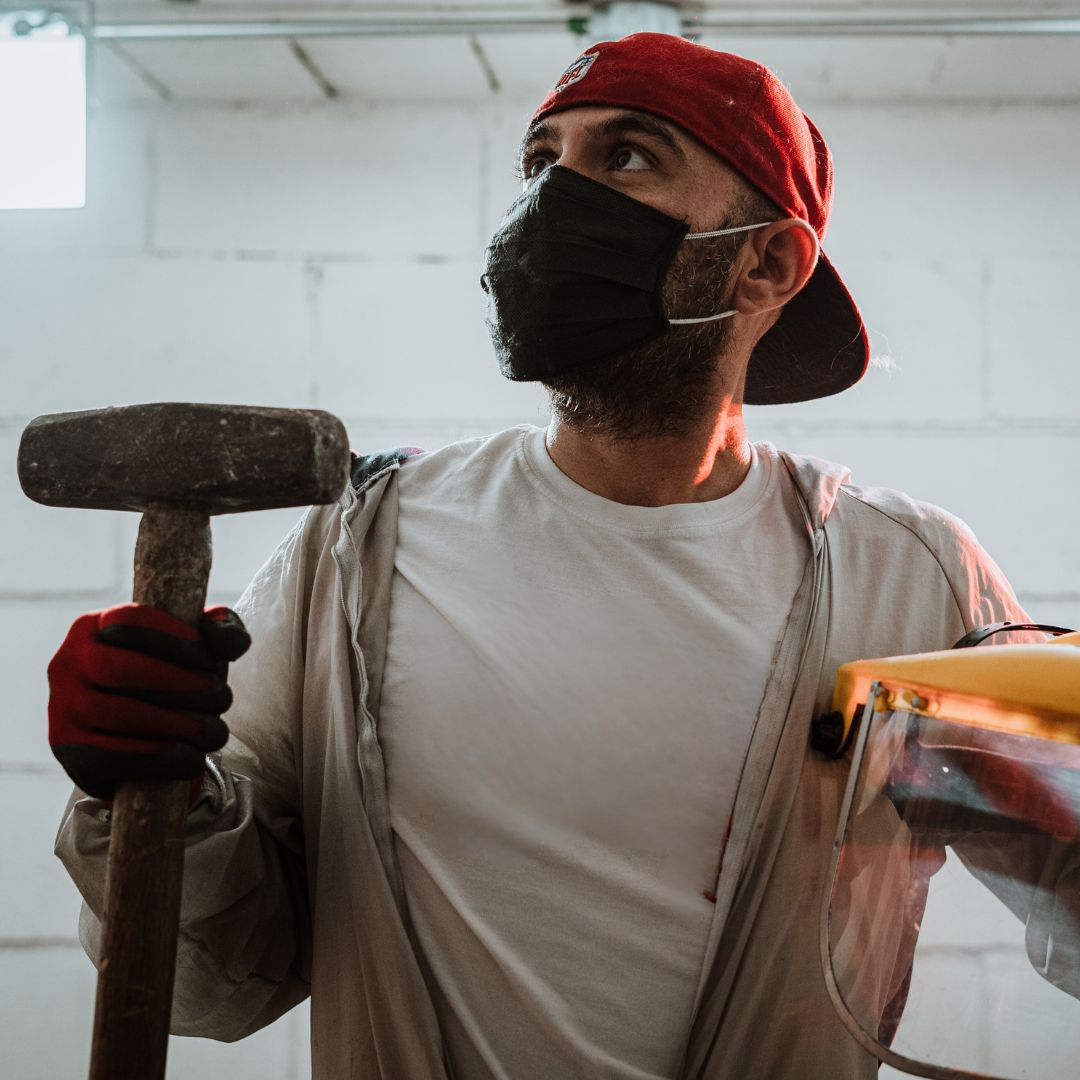 a man in safety gear holding a sledgehammer