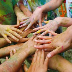 Hands in the middle of a circle of people. hands are covered in paint