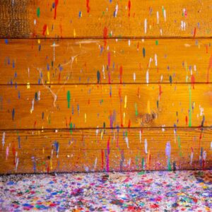 wooden wall and floor below covered in paint splashes