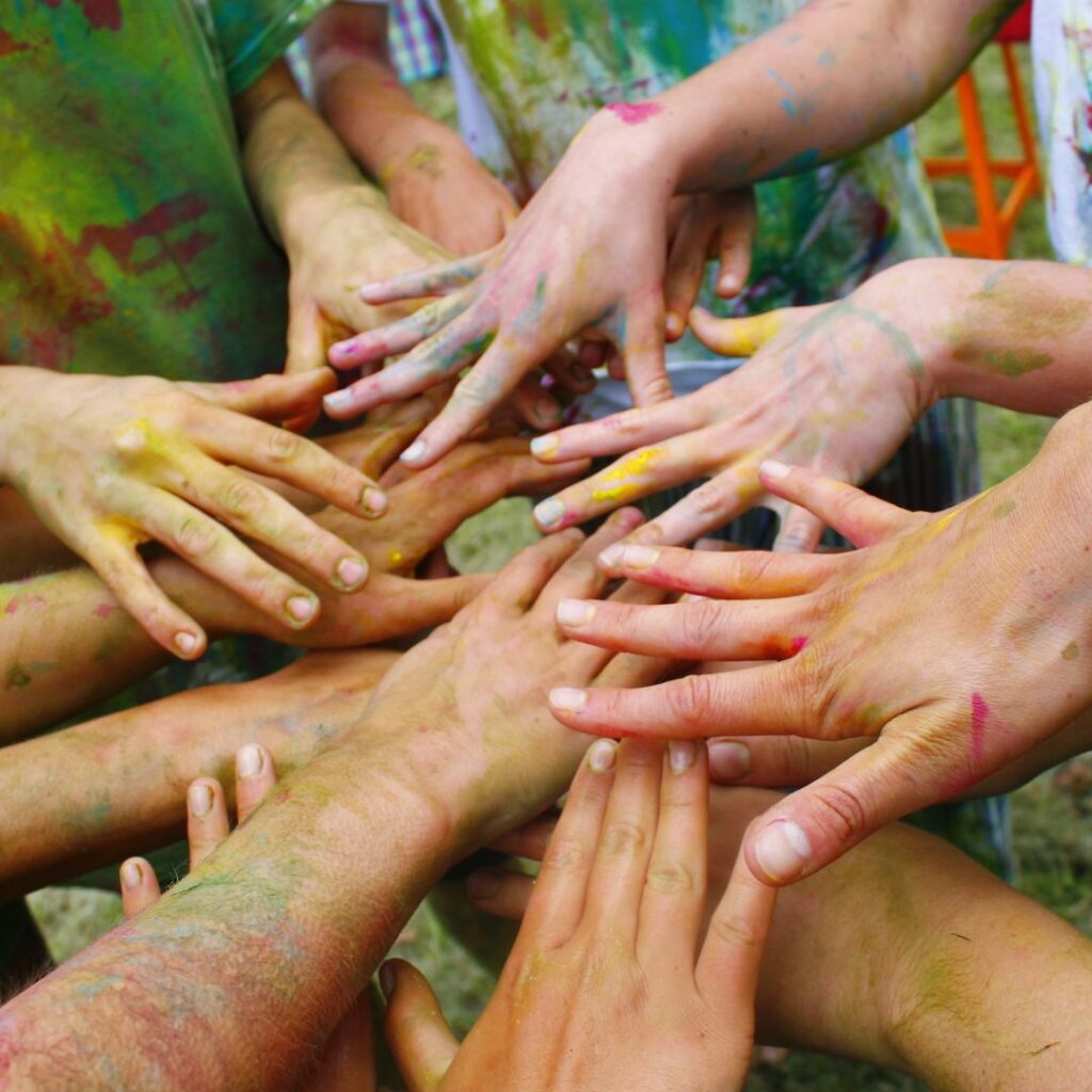 Friends covered in paint putting their hands together in a circle